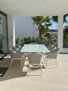 mesa de comedor en aluminio macizo y cristal de 15mm con sillones vogue en apartamento con terraza cubierta en nueva andalucia
