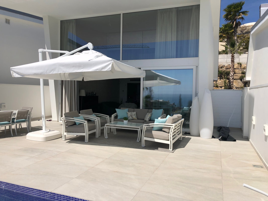 Parasol and set of outdoor sofas and armchairs with waterproof cushions in the Quinta de Benahavis